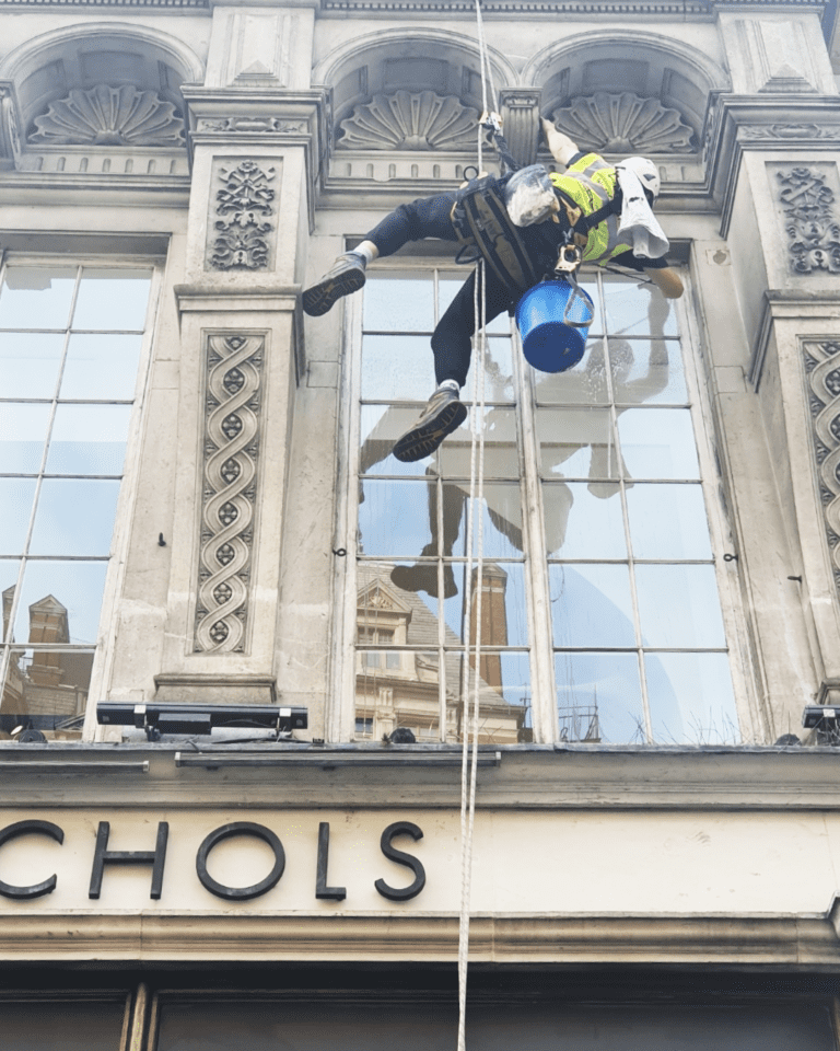 High altitude special services window cleaning technician with safety equipment