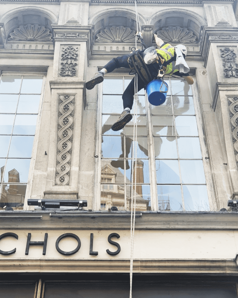High altitude special services window cleaning technician with safety equipment